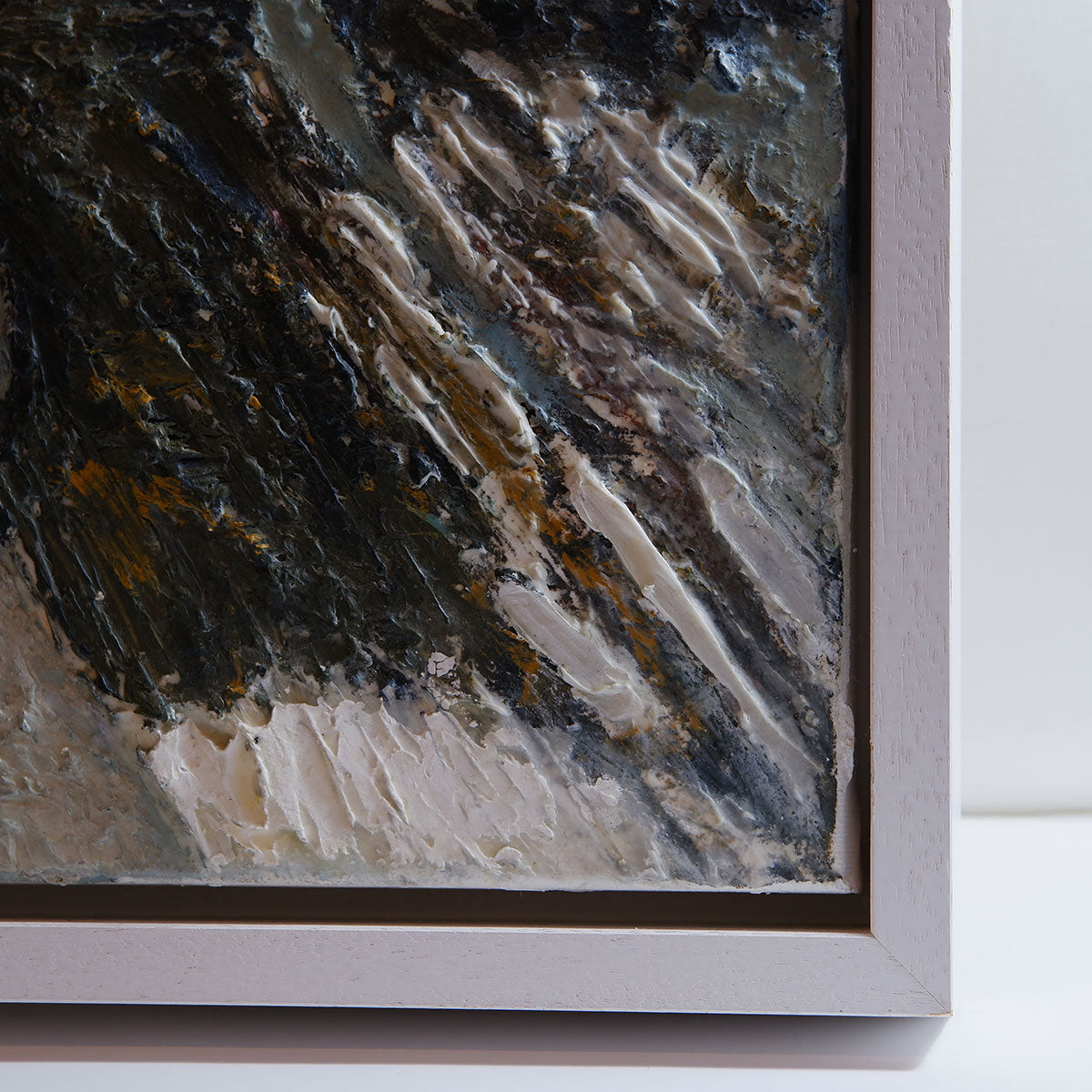 Close-up of a textured painting with a white frame on a light background